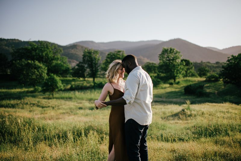 couple kissing in a field.