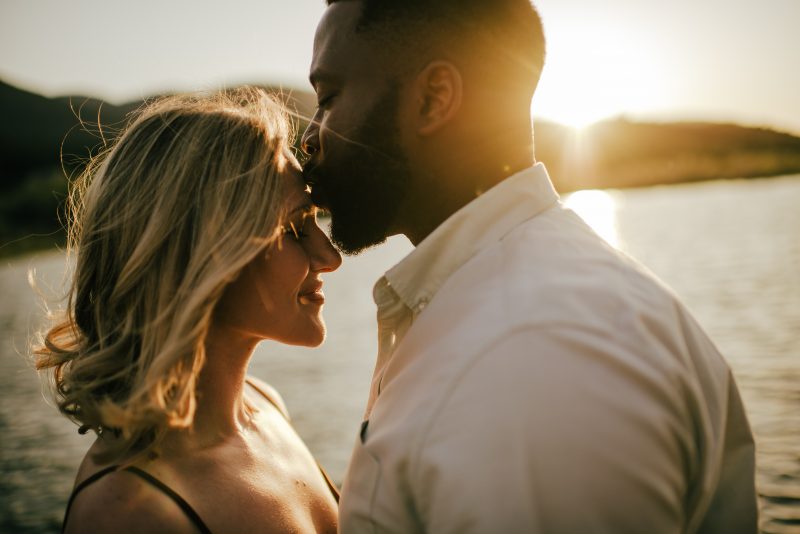 couple kissing at sunset with lake behind them